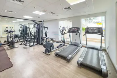 a gym with several treadmills and elliptical machines at Balcony Overlooking the Community, Quick Metro Access,Short 15-Minute Drive to Ibn Battuta Mall, Viktoria Residency, Al Furjan by Deluxe Holiday Homes in Dubai