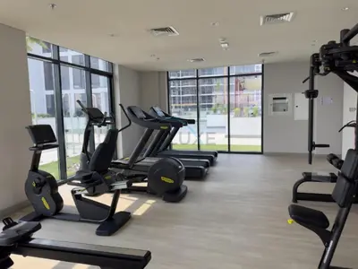 a gym with several treadmills and elliptical machines at Studio Near Meydan Golf Club, 15-Minute Drive to Dubai Mall, Burj Khalifa and Downtown Attractions, Azizi Riviera 46, Al Merkadh by Deluxe Holiday Homes in Dubai
