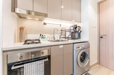 a kitchen with a sink and a washing machine at Studio Near Meydan Golf Club, 15-Minute Drive to Dubai Mall, Burj Khalifa and Downtown Attractions, Azizi Riviera 46, Al Merkadh by Deluxe Holiday Homes in Dubai