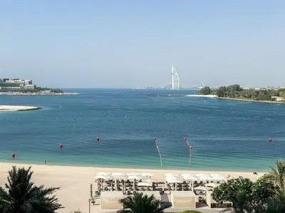 a beach with white umbrellas and a large body of water at Sea View Beachfront 3BR Apartment - Shoreline 6 in Dubai