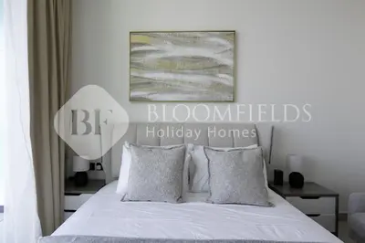 a bedroom with a bed with white sheets and pillows at Bloomfields Cozy Stu Binghatti Azure in Dubai