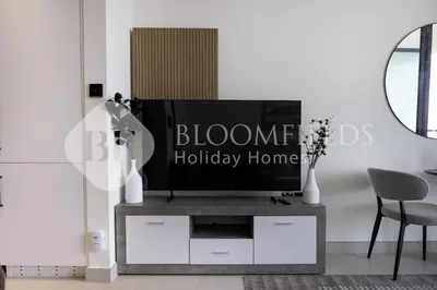 a living room with a television on a tv stand at Bloomfields Cozy Stu Binghatti Azure in Dubai