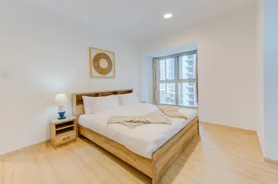 a white bedroom with a bed and a window at Boho Style 2BHK Apartment With Sea View Next to Tram Station in Dubai