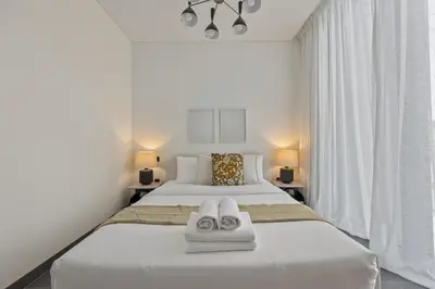 a white bedroom with two towels on a bed at Modern Apartment with Balcony and Pool Access in Dubai