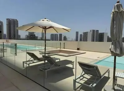 a patio with chairs and an umbrella and a pool at High Rise Studio Pool Gym Binghatti Gardenia JVC in Dubai
