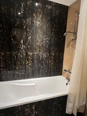 a bathroom with a white tub and a black wall at Cozy Spacious Studio in Downtown with Burj Khalifa View in Dubai