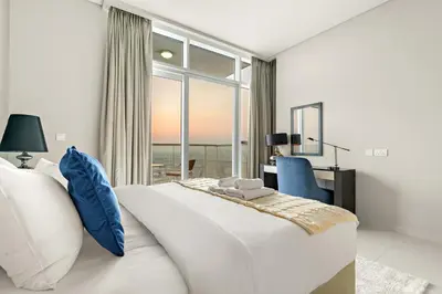 a white bedroom with a large bed and a window at Spacious 1BR with Huge Terrace in Dubai