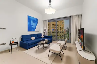a living room with a blue couch and a tv at Spacious 1BR in Downtown with Balcony & Pool in Dubai