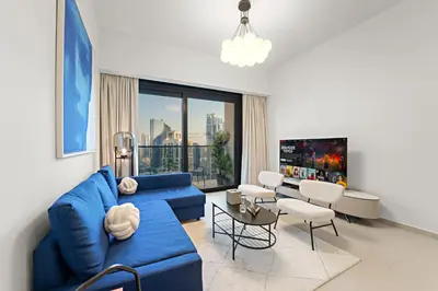 a living room with a blue couch and a large window at Spacious 1BR in Downtown with Balcony & Pool in Dubai