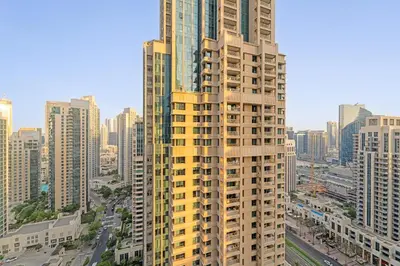 a tall yellow building in the middle of a city at Spacious 1BR in Downtown with Balcony & Pool in Dubai
