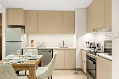 a kitchen with a wooden table and chairs and a kitchen with white cabinets at FIRST CLASS 1BR Creek Beach , Relaxing Vibes in Dubai