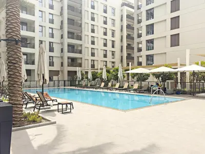 a swimming pool with chairs and umbrellas next to a building at FIRST CLASS 1BR Creek Beach , Relaxing Vibes in Dubai