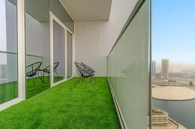 a balcony with chairs and green grass in a building at FIRST CLASS 1BR Canal View Escape in Dubai