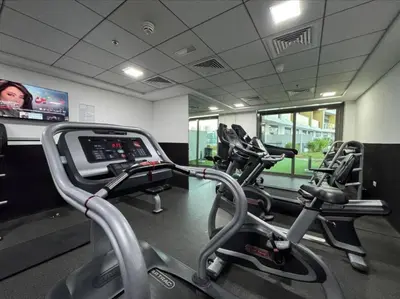 a gym with three cardio machines and a tv at FIRST CLASS Studio Stylish & Cozy JVC Escape in Dubai