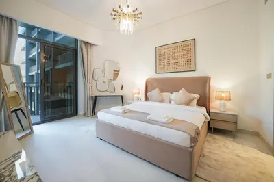a bedroom with a large bed and a chandelier at EasyGo - Modern 1BR with Balcony & Amenities in Arjan in Dubai
