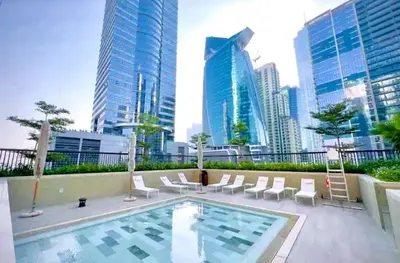 a swimming pool with white chairs and a city skyline at Cosy flat in the heart of Dubai in Dubai