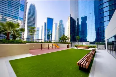 a park with benches and grass in a city at Cosy flat in the heart of Dubai in Dubai