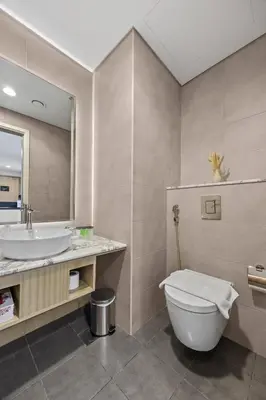 a bathroom with a sink and a toilet and a mirror at Paramount Midtown, Luxury 1BR with Infinity Pool with Burj View in Dubai