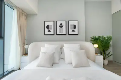 a white bedroom with a white bed with white pillows at Gala Guests - Golf Gate Residences with Panoramic Golf Views in Dubai