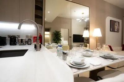a white table with plates and glasses on it at Designer 1BR Apt with Modern and Airy Layout in Dubai