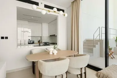 a kitchen and dining room with a wooden table and chairs at VayK - Modern 2BD Retreat with Private Pool in JVC in Dubai
