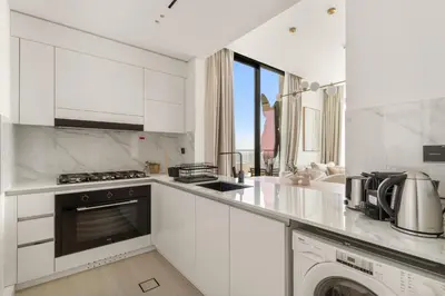 a white kitchen with a stove and a dishwasher at VayK - Modern 2BD Retreat with Private Pool in JVC in Dubai