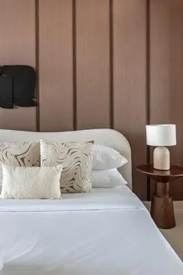a white bed with pillows and a table with a lamp at GuestReady - Balcony with Jacuzzi | Canal View in Dubai