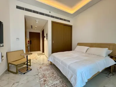 a bedroom with a bed and a table and a chair at Stylish Studio In Azizi Riviera 59 in Dubai