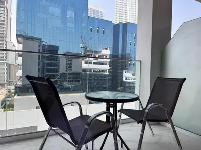 a table and chairs on a balcony with a view of a city at Stylish Studio In Azizi Riviera 59 in Dubai