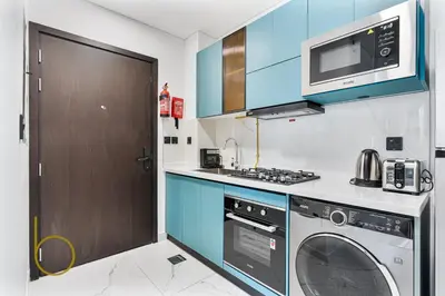 a kitchen with a washing machine and a microwave at Bookable Stylish Dubai escape with private pool in Dubai