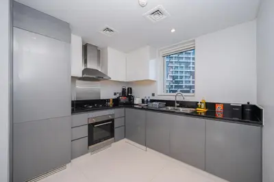 a kitchen with stainless steel appliances and a window at Cozy Waterfront Studio Pool, Gym, Parking in Dubai