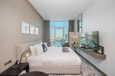 a hotel room with a large bed and a large window at Cozy Waterfront Studio Pool, Gym, Parking in Dubai