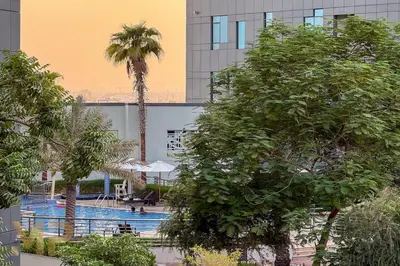 a swimming pool with palm trees in front of a building at Marcopolo - Experience modern living in Business Bay Dubai in Dubai