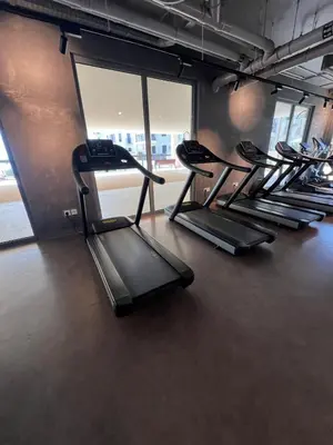a row of treadmills in a gym with windows at Coastal Haven 1BDR in La Cote B4-12 in Dubai