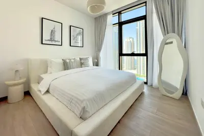 a white bedroom with a large bed and a large window at Luxury 1 Bed Apt in Palace, Dubai Creek Harbour in Dubai