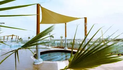 a pool with an umbrella and a palm tree at HAVN - Studio in Al Jawhara, JVT in Dubai