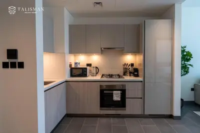 a kitchen with white cabinets and a stove top oven at Luxury 1BR Burj Khalifa & Flamingo Sanctuary Views in Dubai