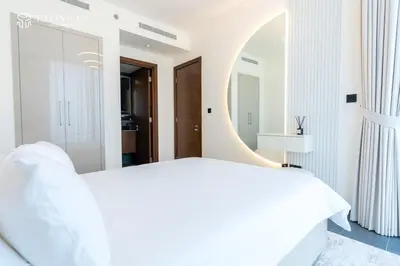 a bedroom with a white bed and a round mirror at Luxury 1BR Burj Khalifa & Flamingo Sanctuary Views in Dubai
