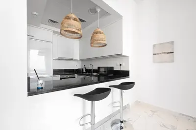 a white kitchen with black counter tops and stools at Luxury Leisure Massive Pool Oasis in Amna Tower in Dubai