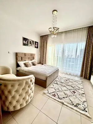 a bedroom with a bed and a chair and a window at Spacious Modern High Floor Independent Studio Downtown in Dubai
