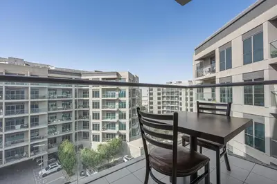 a balcony with a table and chairs and a large building at Brand New Designer Space with All Modern Amenities in Dubai