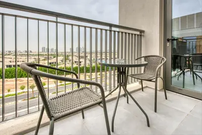 a balcony with a table and chairs and a view of the city at Fresh 2BR at Mudon Views 4, Dubailand by Deluxe Holiday Homes in Dubai