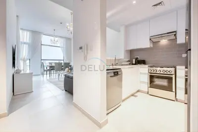 a kitchen with white appliances and a living room at Fresh 2BR at Mudon Views 4, Dubailand by Deluxe Holiday Homes in Dubai