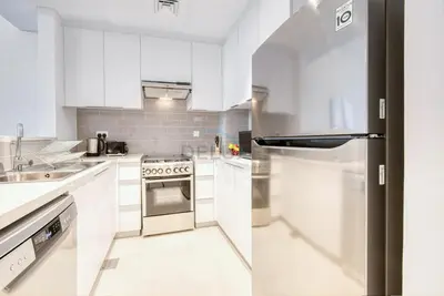 a kitchen with white cabinets and a stainless steel refrigerator at Fresh 2BR at Mudon Views 4, Dubailand by Deluxe Holiday Homes in Dubai