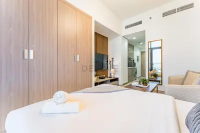 a bedroom with a large white bed and a living room at Studio Near Meydan Racecourse and Golf Club with Convenient Access to Al Meydan Road and Dubai Top Attractions, Azizi Riviera 29, Al Merkadh by Deluxe Holiday Homes in Dubai