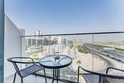 a balcony with a table and chairs and a view of a city at Studio Near Meydan Racecourse and Golf Club with Convenient Access to Al Meydan Road and Dubai Top Attractions, Azizi Riviera 29, Al Merkadh by Deluxe Holiday Homes in Dubai