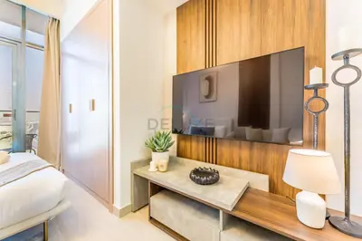a bedroom with a bed and a tv on a wall at Studio Near Meydan Racecourse and Golf Club with Convenient Access to Al Meydan Road and Dubai Top Attractions, Azizi Riviera 29, Al Merkadh by Deluxe Holiday Homes in Dubai