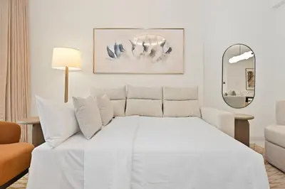 a white bedroom with a white bed and a mirror at Newly Styled 1BD in Grand Bleu Beachfront, Fits 4 in Dubai