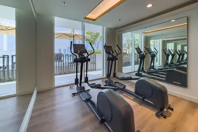 a gym with treadmills and ellipticals in a room with windows at Prime 1 Bedroom with Private Beach in Beachfront in Dubai