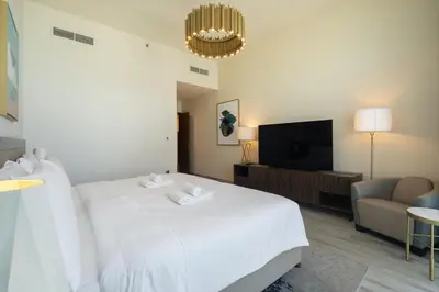 a bedroom with a white bed and a flat screen tv at Luxury 2BHK Sea & Palm Views 20th Floor Tram line in Dubai
